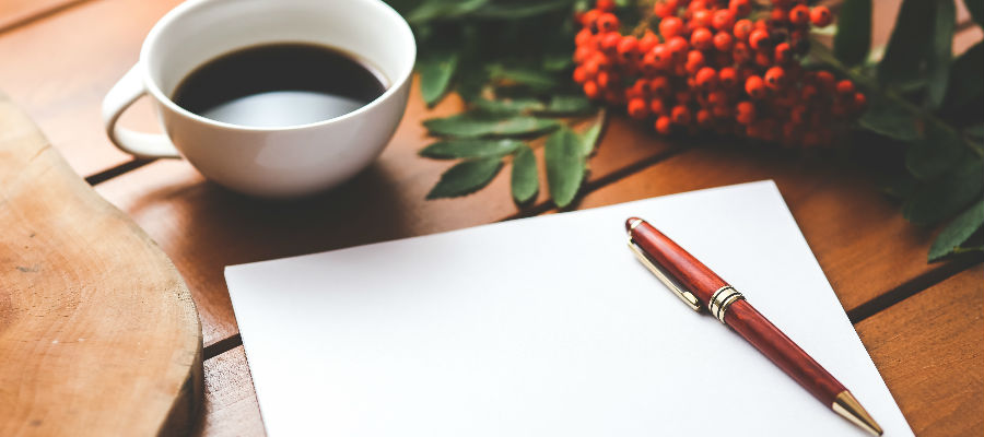 Coffee cup with pen and paper