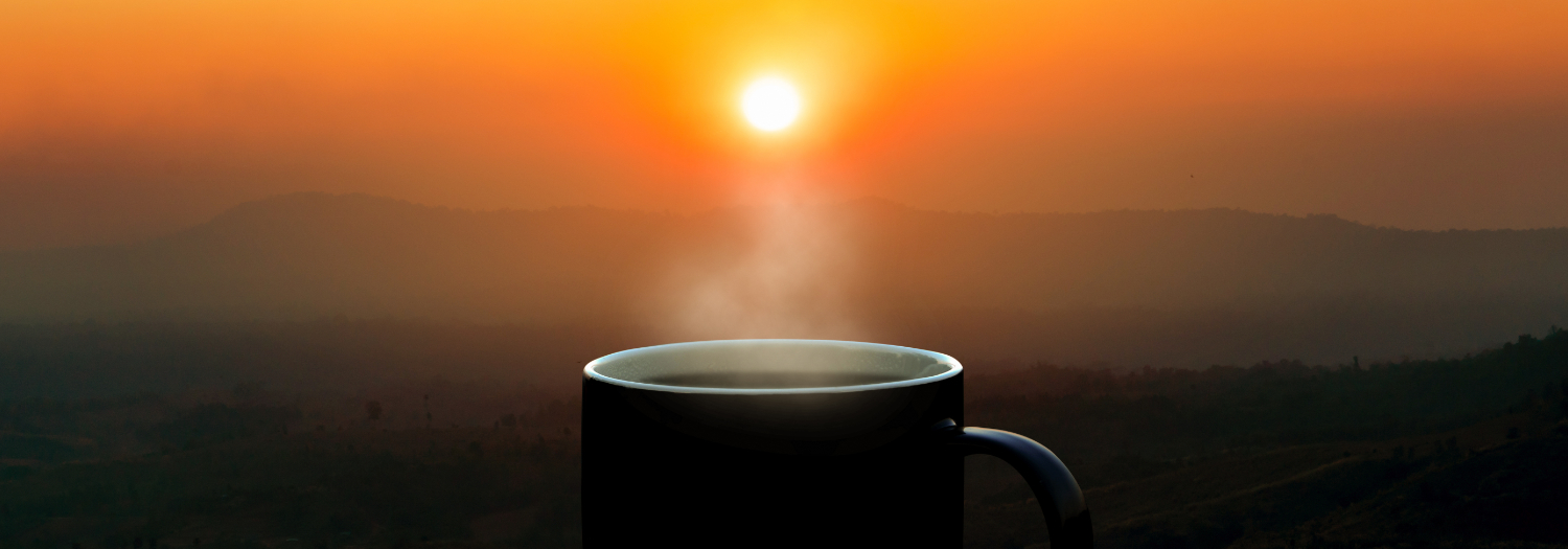 sun rising with coffee mug in foreground